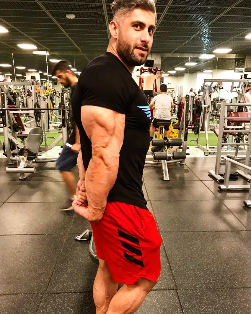 Ahmad Parvin flexing his huge and ripped triceps in a gym