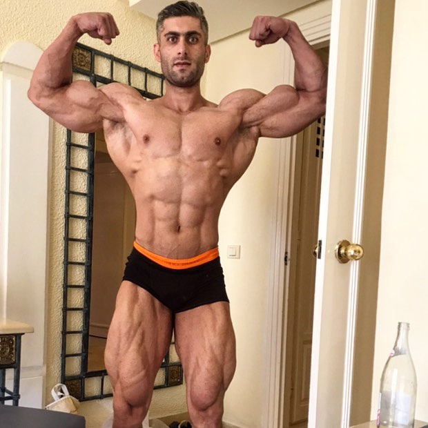 Ahmad Parvin flexing front double biceps in his house