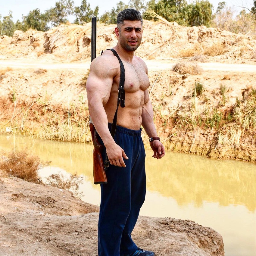 Ahmad Parvin standing shirtless near a river looking ripped
