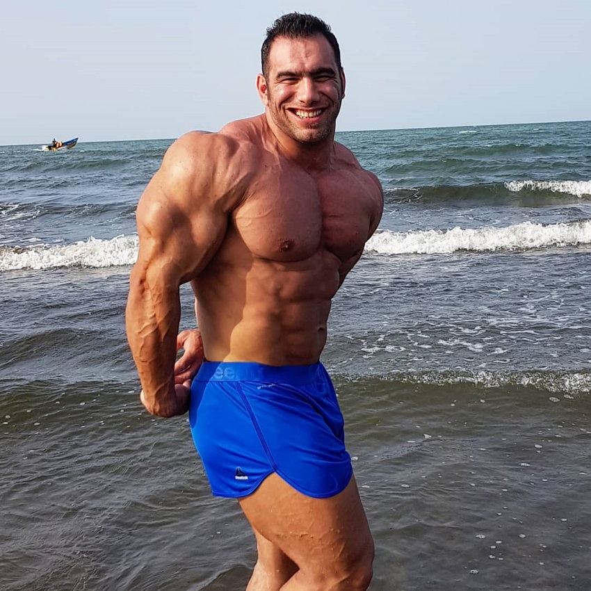 Ayat Bagheri doing a side triceps pose on the beach