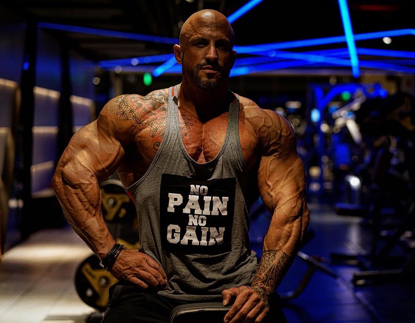 Benjamin Radic posing in a tank top in a gym, looking muscular and ripped