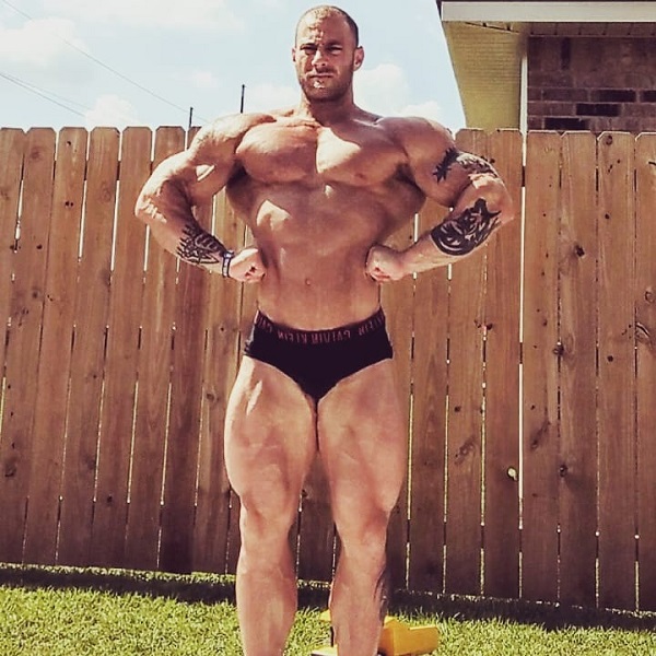 Caleb Blanchard doing a shirtless front lat spread in his backyard