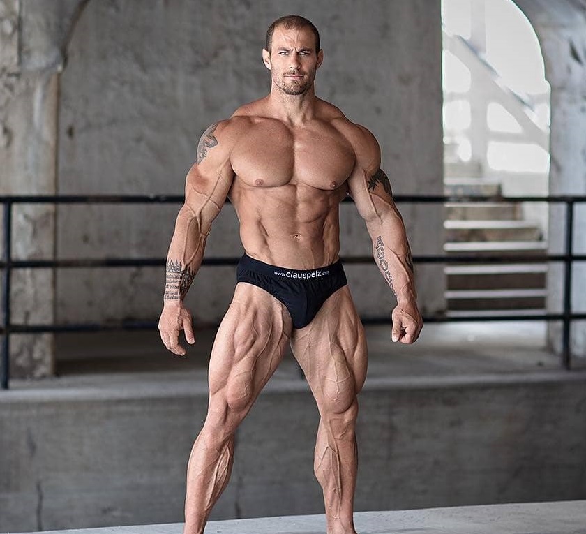 Caleb Blanchard posing shirtless in a building complex