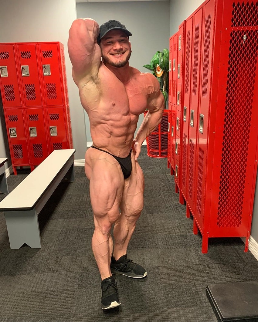 Hunter Labrada flexing his muscles in a locker room looking ripped