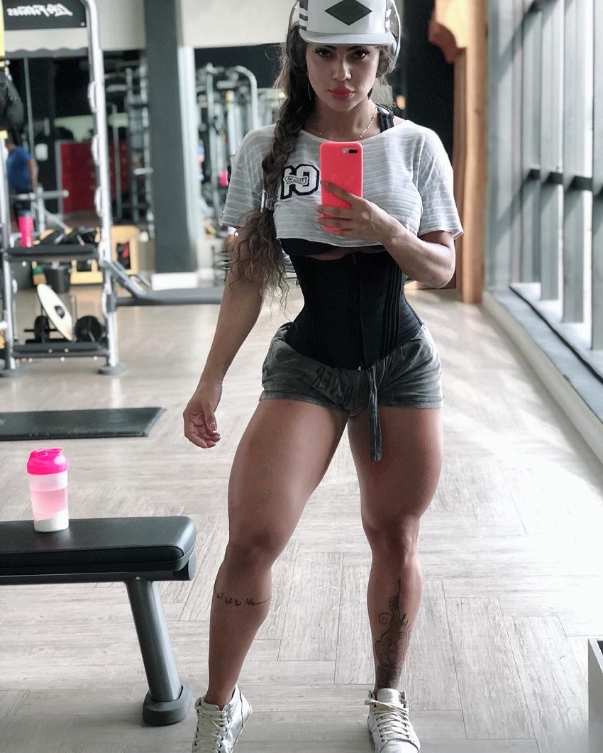 Nadia Brandao taking a photo of her toned legs in a gym