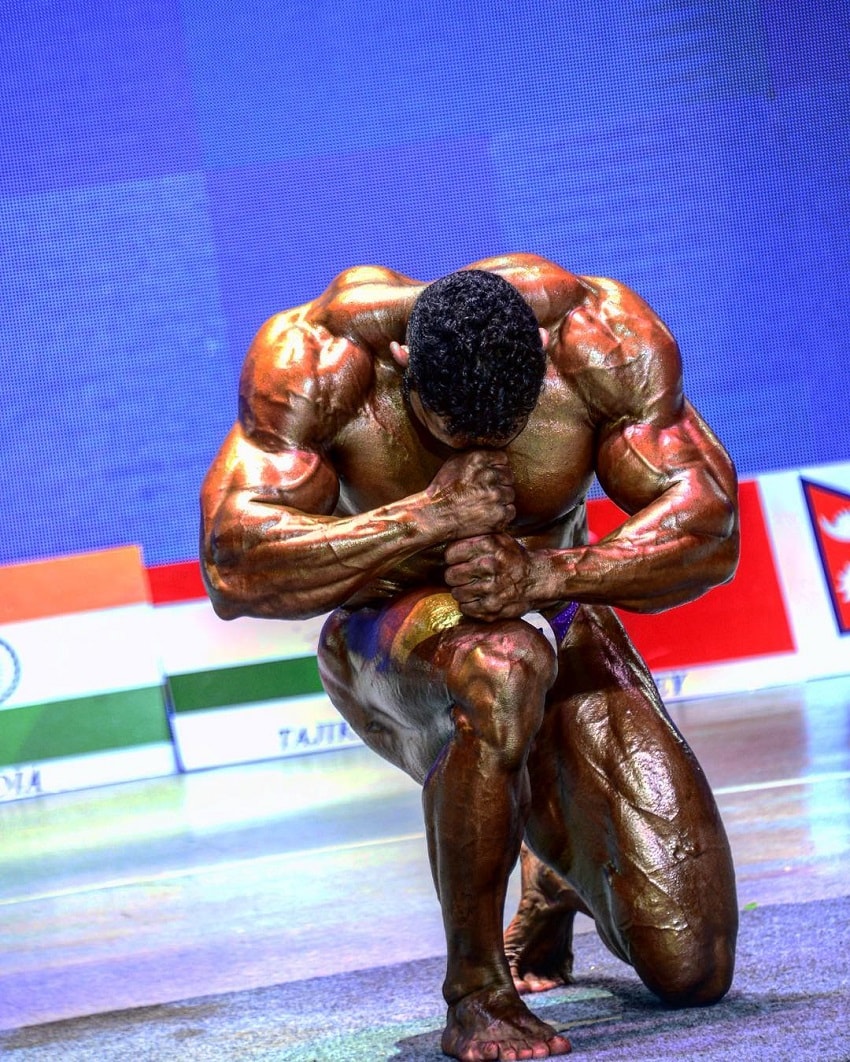 Yasin Qaderi performing a pose on a bodybuilding stage