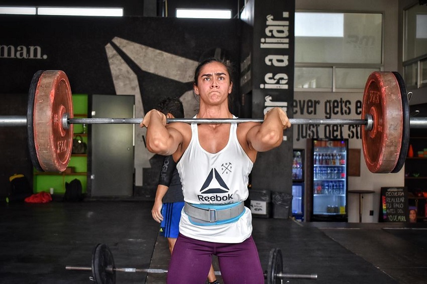 Yazmin Arroyo Loaiza doing a heavy overhead barbell press looking mentally focused and strong