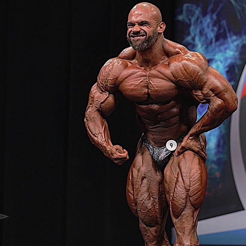 Alexis Rivera Rolon doing a most muscular pose on the bodybuilding stage, looking insanely ripped