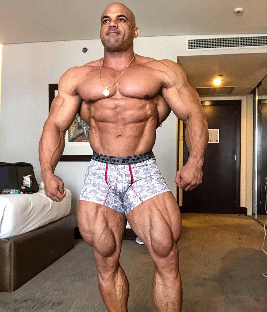 Alexis Rivera Rolon posing shirtless in his apartment, looking huge and ripped