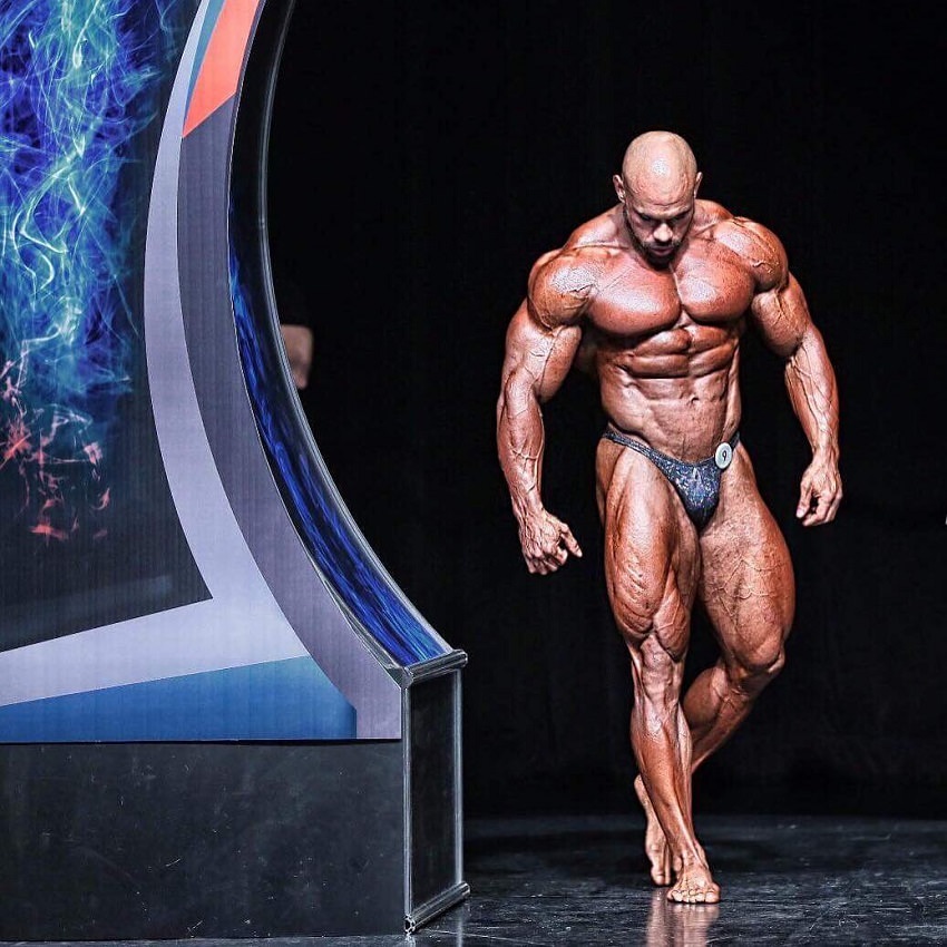 Alexis Rivera Rolon walking onto the bodybuilding stage, looking ripped and huge