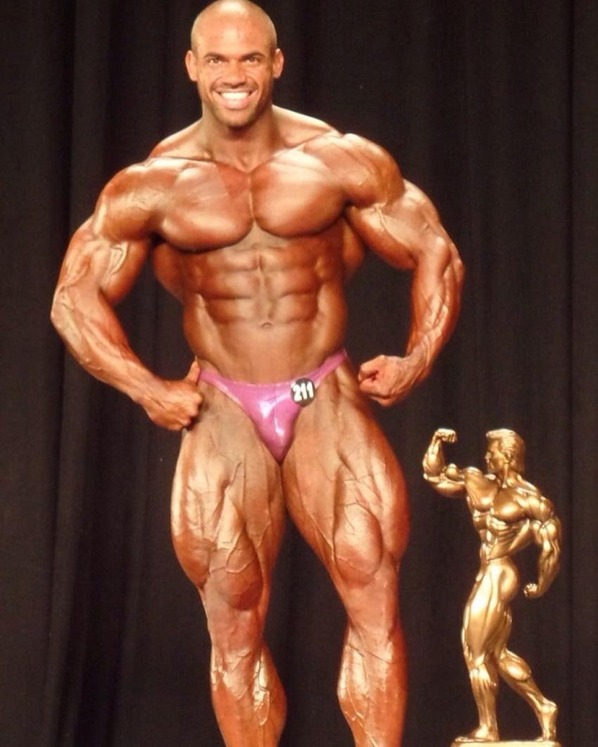 Alexis Rivera Rolon posing victorious with an Arnold Trophy at the NPC Nationals