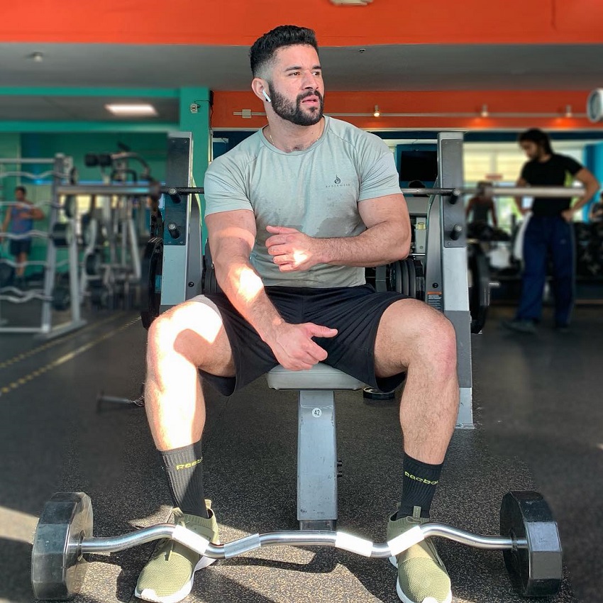 Bremen Menelli sitting on a bench in the gym with a barbell in front of him