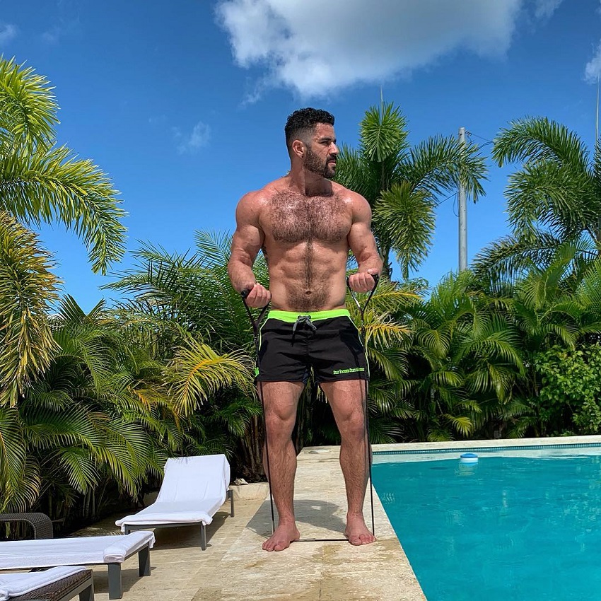 Bremen Menelli training shirtless with resistance bands by a pool