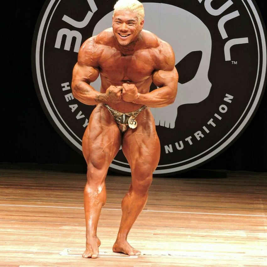 Caio Eiji Sirahata flexing on the bodybuilding stage