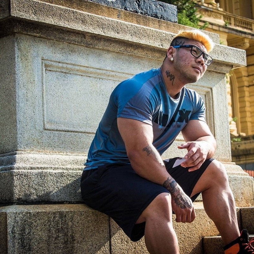 Caio Eiji Sirahata sitting near a statue looking strong and well-built