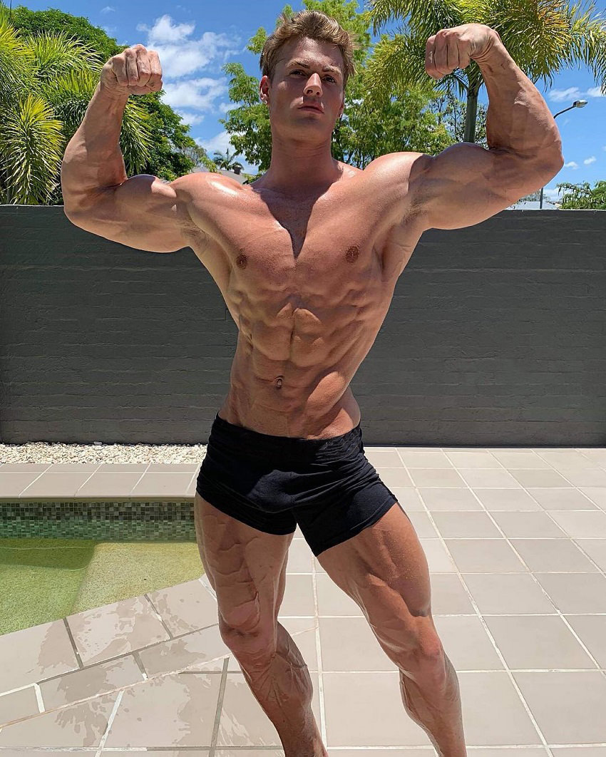 Carlton Loth doing a shirtless front double biceps pose for the photo