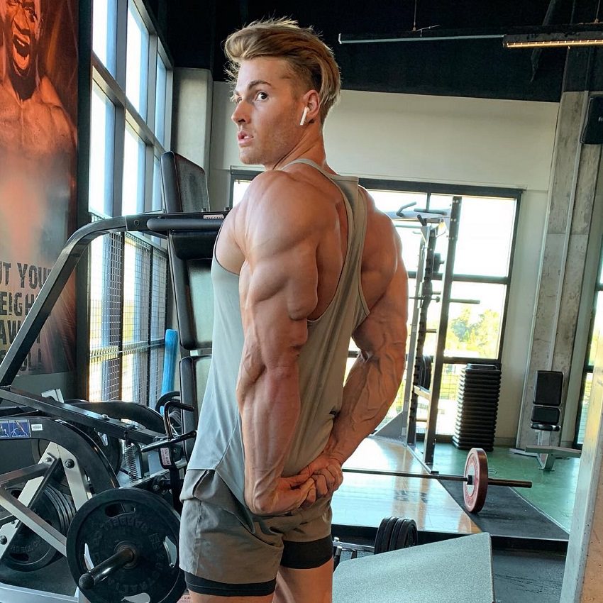 Carlton Loth flexing his ripped and bulging triceps in a gym