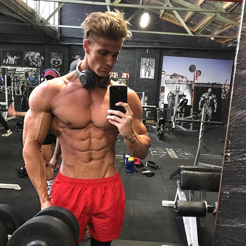 Carlton Loth taking a shirtless selfie in the gym looking ripped