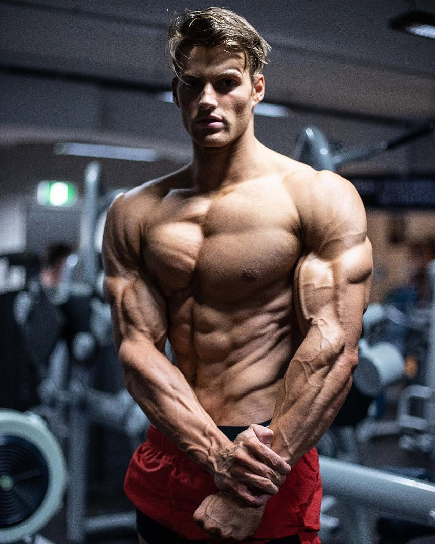 Carlton Loth flexing shirtless in the gym