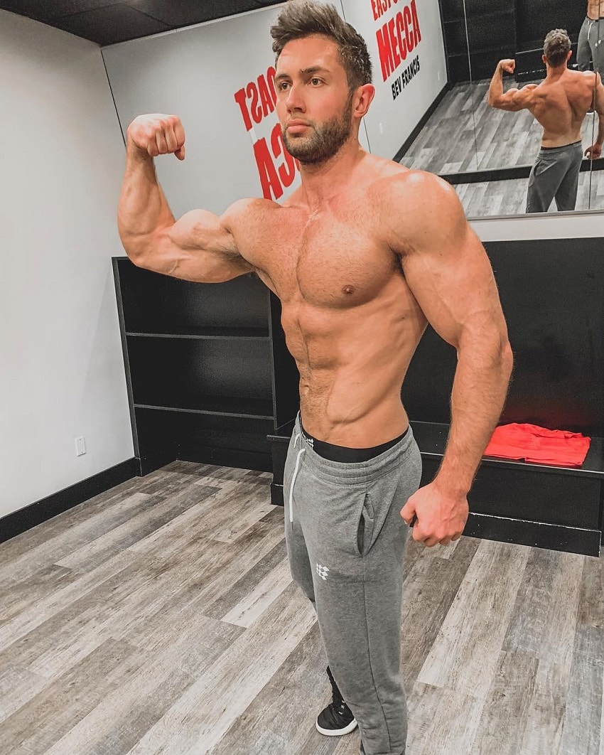 Daniel Zukich flexing his biceps in an empty room