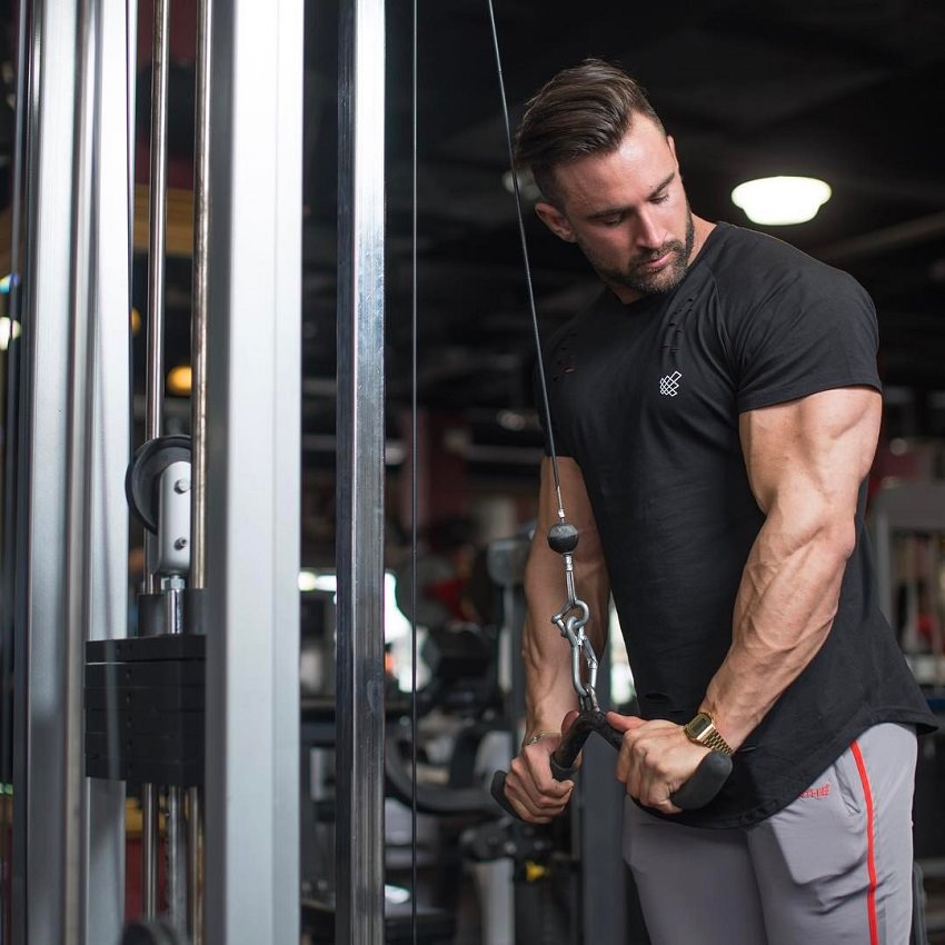 Dylan Thomas doing cable triceps extension in a gym