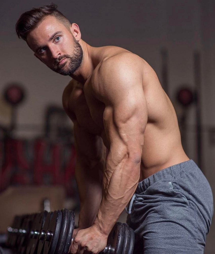 Dylan Thomas training shirtless with a dumbbell