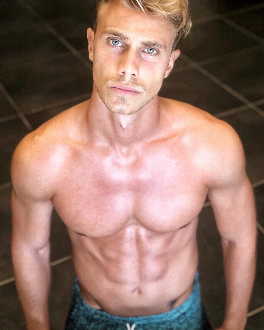 Edoardo Santonocito posing shirtless with a serious expression on his face, looking fit and lean