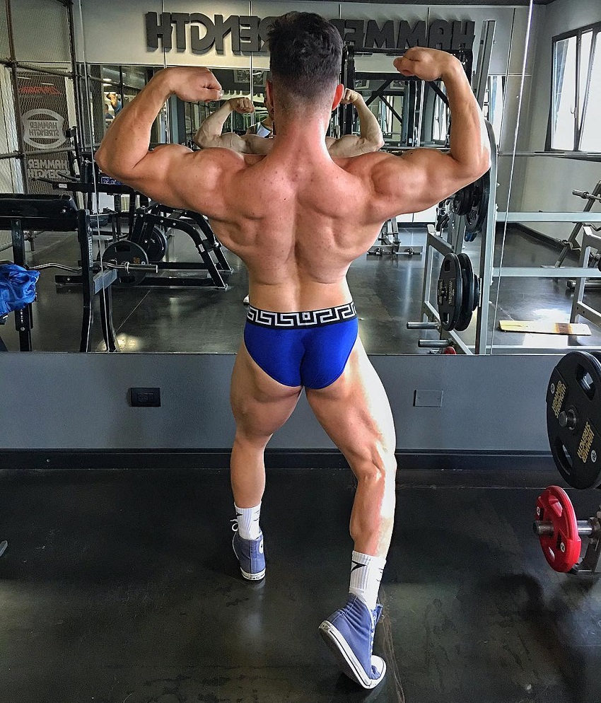 Francesco Della Vedova performing a back double biceps pose for the camera, looking ripped and muscular