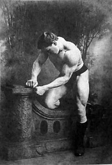 George Hackenschmidt posing shirtless in an old, picturesque black and white photo, showing off his strong muscles