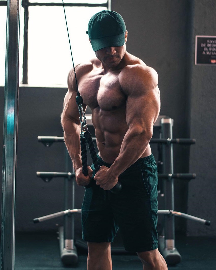 Ismael Martinez performing cable triceps extensions while shirtless, looking huge and ripped
