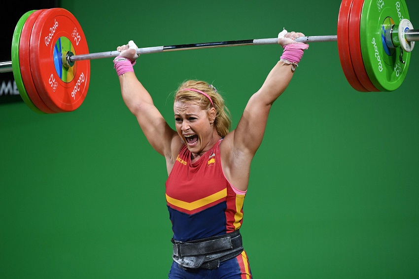 Lidia Valentin Perez performing an extremely heavy overhead press during Olympics weightlifting contest, having a pained grimace