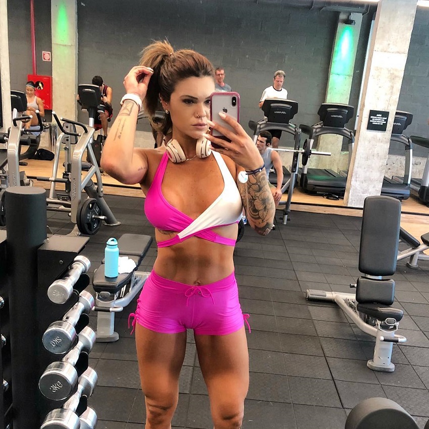 Marcela Moura capturing a photo of herself in a gym mirror