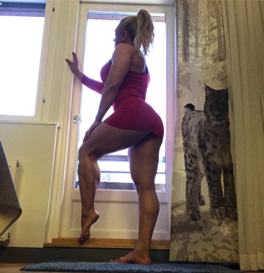 Minna Pajulahti posing by a door in the house, her legs looking curvy and fit