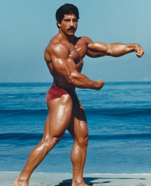 Ray Mentzer flexing shirtless on the beach looking huge and ripped