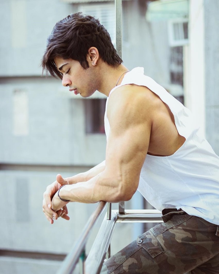 Vasu Mittal looking down the street from his balcony, his arms looking huge and ripped