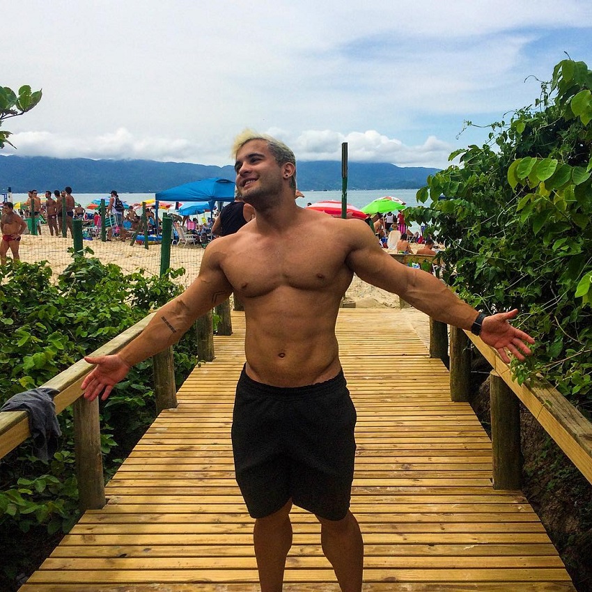 Ernane Guimaraes shirtless, walking down the beach resort, looking happy and fit