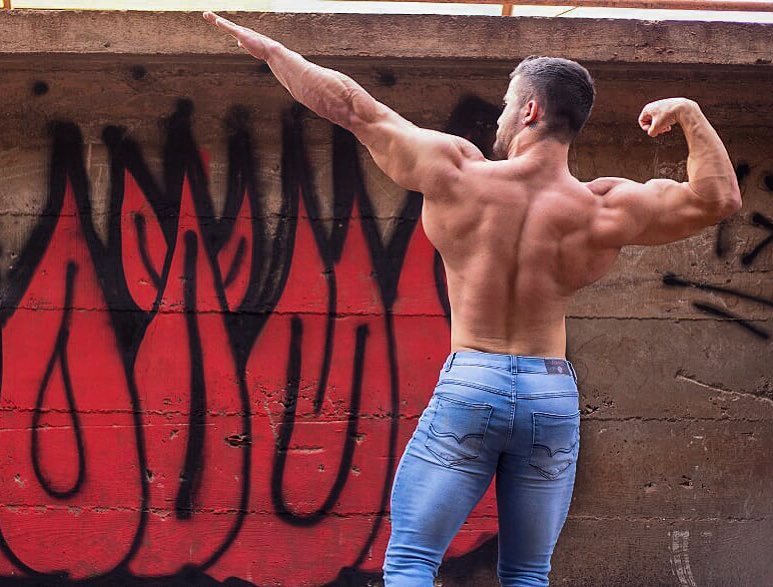 Ernane Guimaraes striking a Frank Zane and 'Zyzz' pose from the back, looking ripped and aesthetic