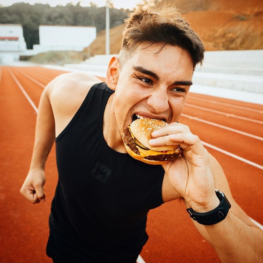 Gabriel Arones eating a burger outdoors on a track field