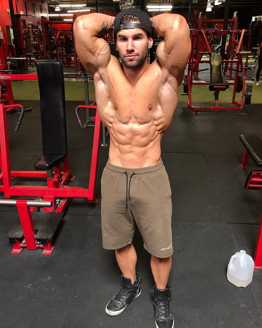 Jake Burton flexing his abs shirtless in the gym