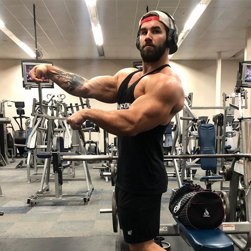 Jake Burton flexing his arms old-school Arnold style while standing in the gym