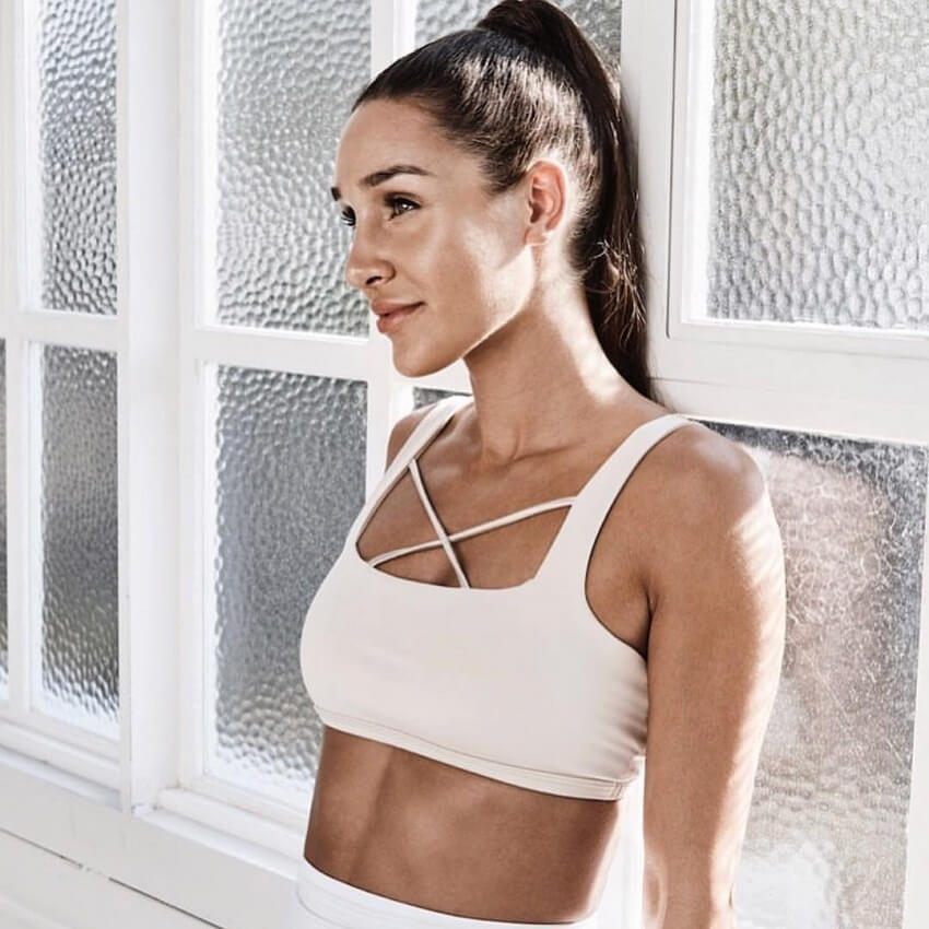 Kayla Itsines smiling and looking lean in a fitness photo shoot