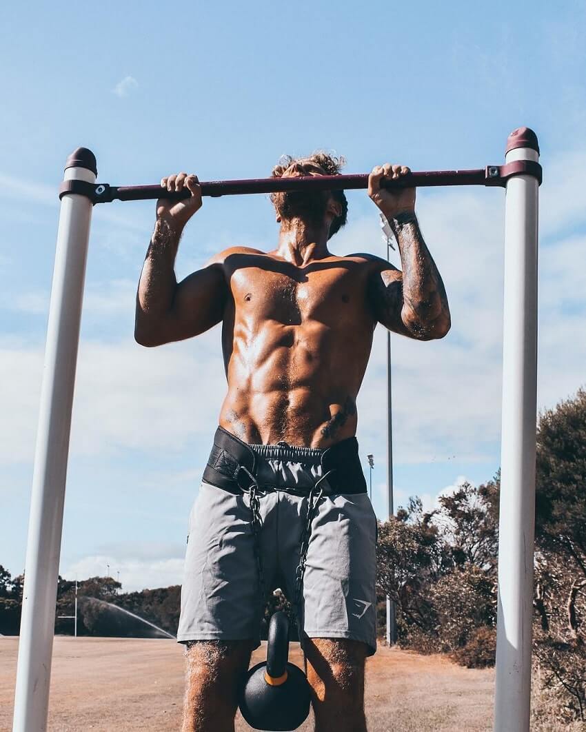 Matt Fox doing pull ups on the bar, looking ripped and fit