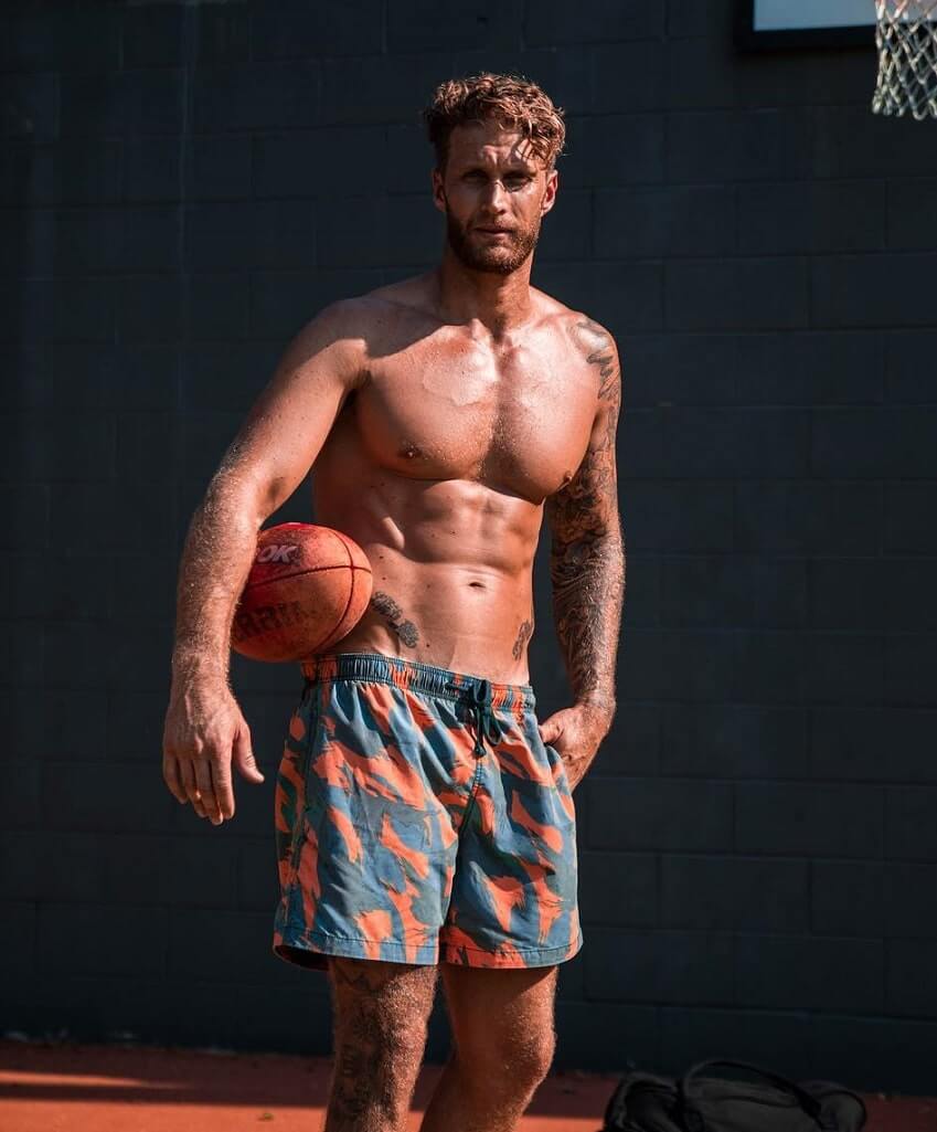 Matt Fox standing shirtless in the sun with a basket ball in his hand, looking muscular and ripped