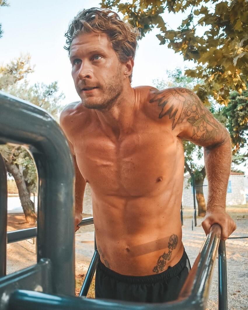 Matt Fox doing dips shirtless, looking strong and fit