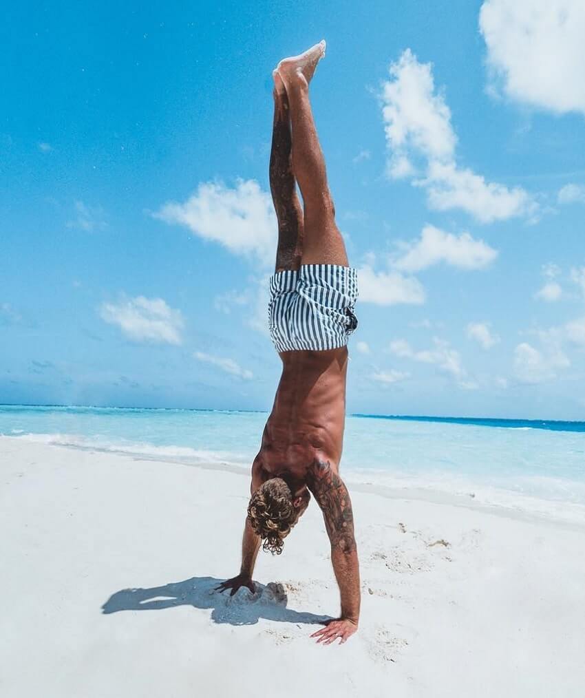 Matt Fox doing handstands shirtless on the beach