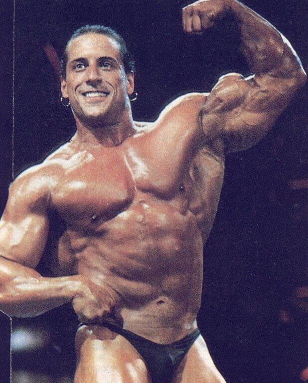 Mike Quinn flexing his biceps on the bodybuilding stage