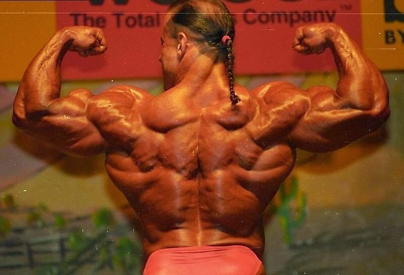 Mike Quinn flexing his back and arm muscles on the bodybuilding stage