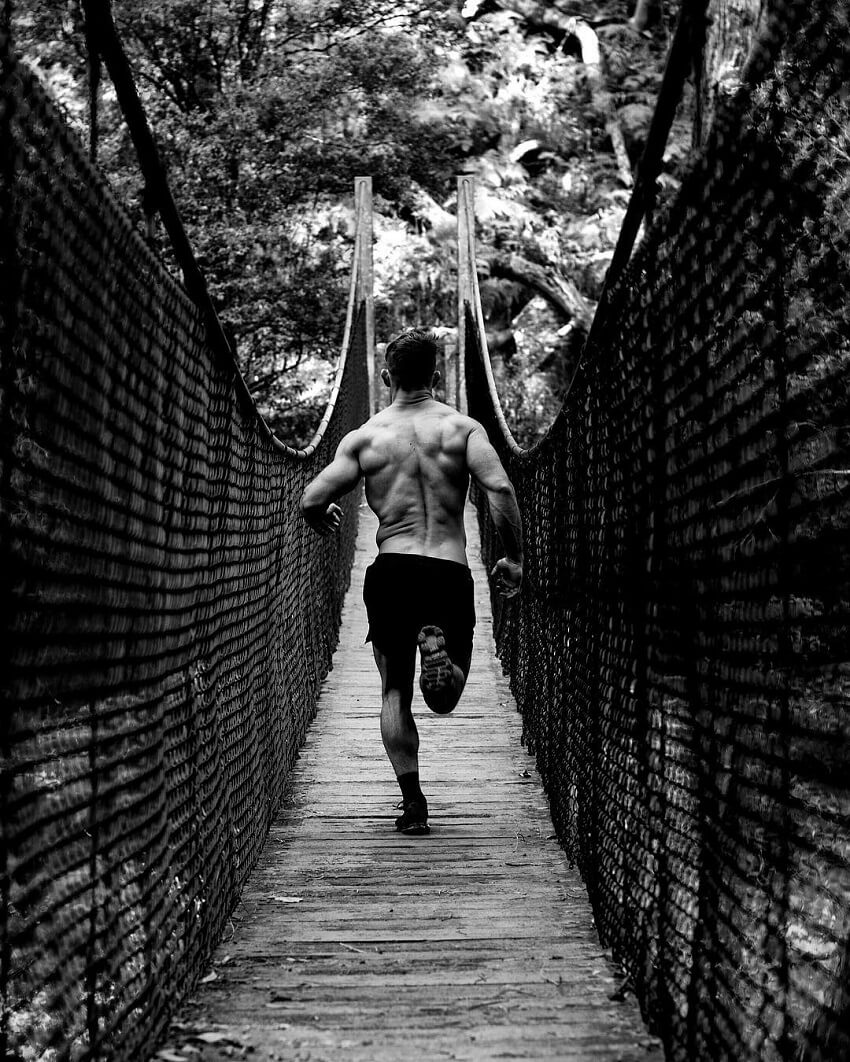 Nathan McCallum running shirtless across a bridge, looking fit and ripped