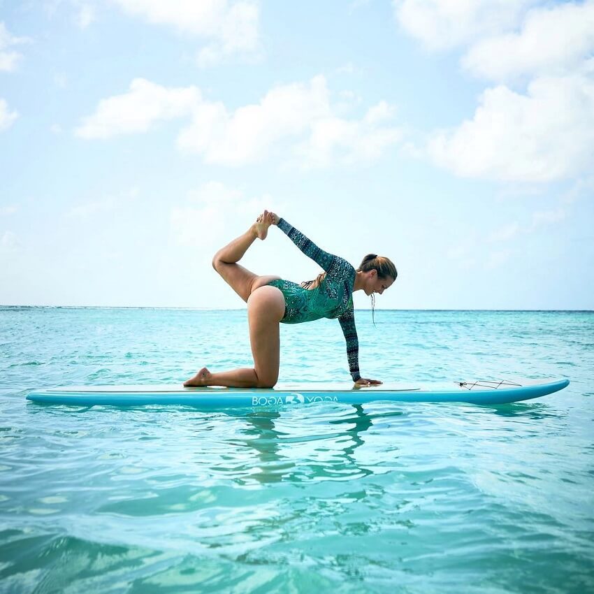 Rachel Brathen doing yoga on a surfboard