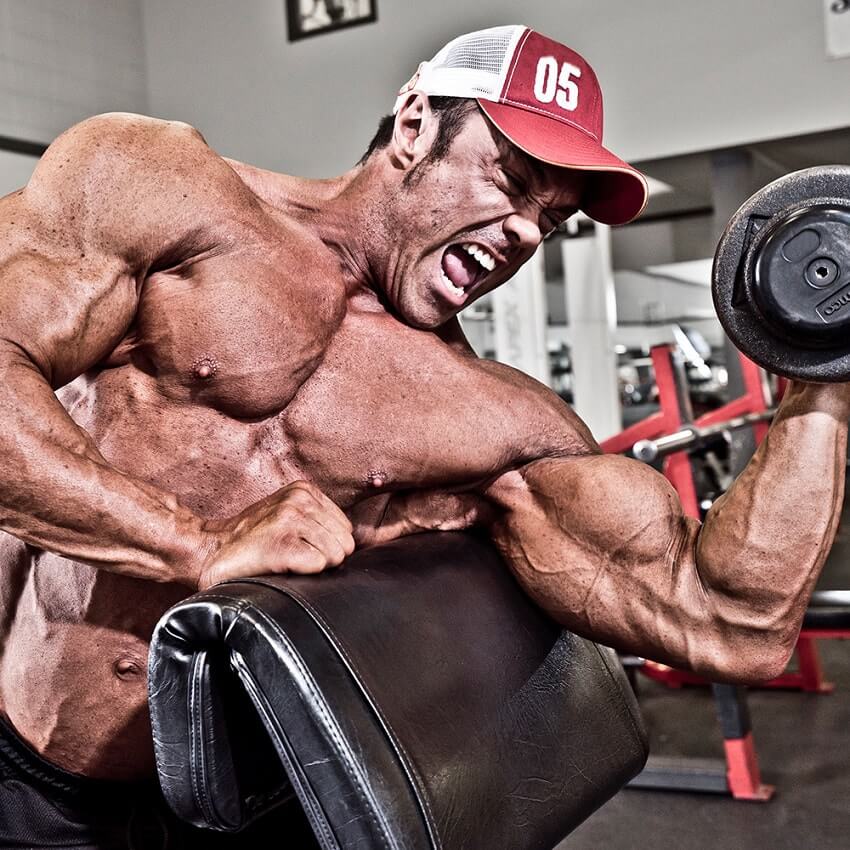 Ron Partlow doing biceps curls with a pained grimace